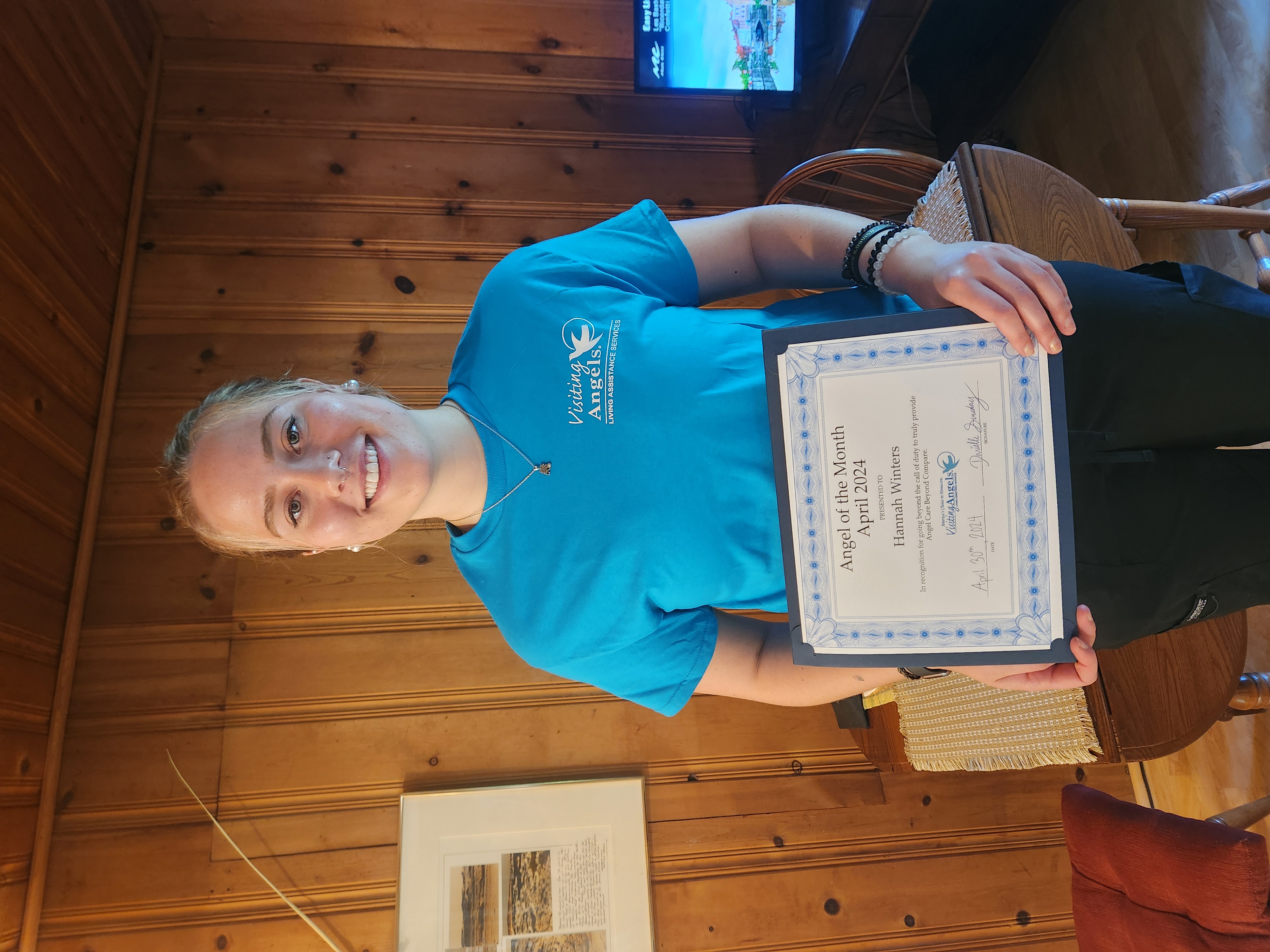 Hannah Winters smiles and shows her printed award for Angel of the Month for excellent caregiving in home care to clients in Allegan, Kalamazoo, Mattawan, Paw Paw, Plainwell, Portage, and Southwest Michigan.