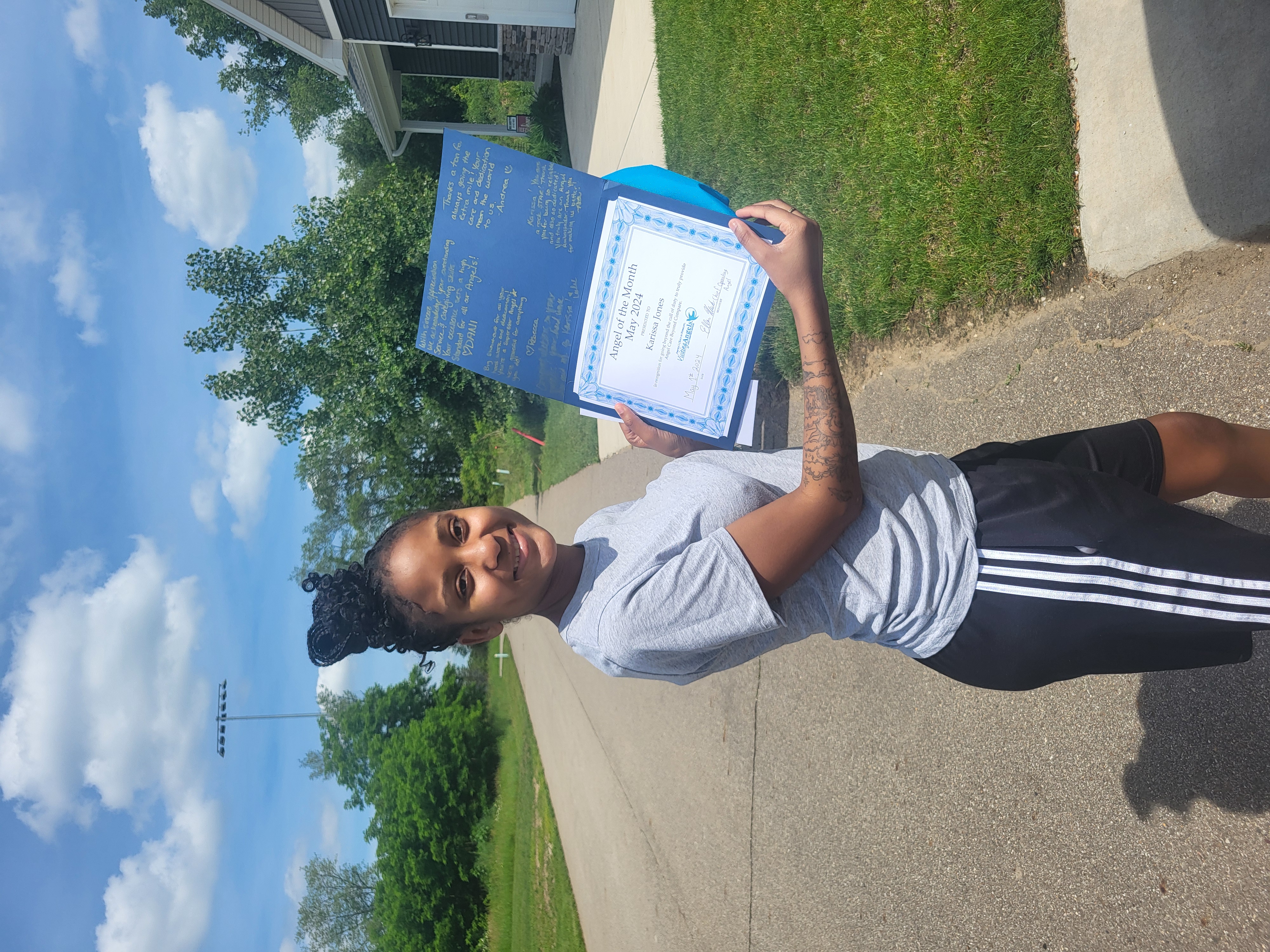 Karissa Jones smiles and shows her printed award for Angel of the Month for excellent caregiving in home care to clients in Allegan, Kalamazoo, Mattawan, Paw Paw, Plainwell, Portage, and Southwest Michigan.