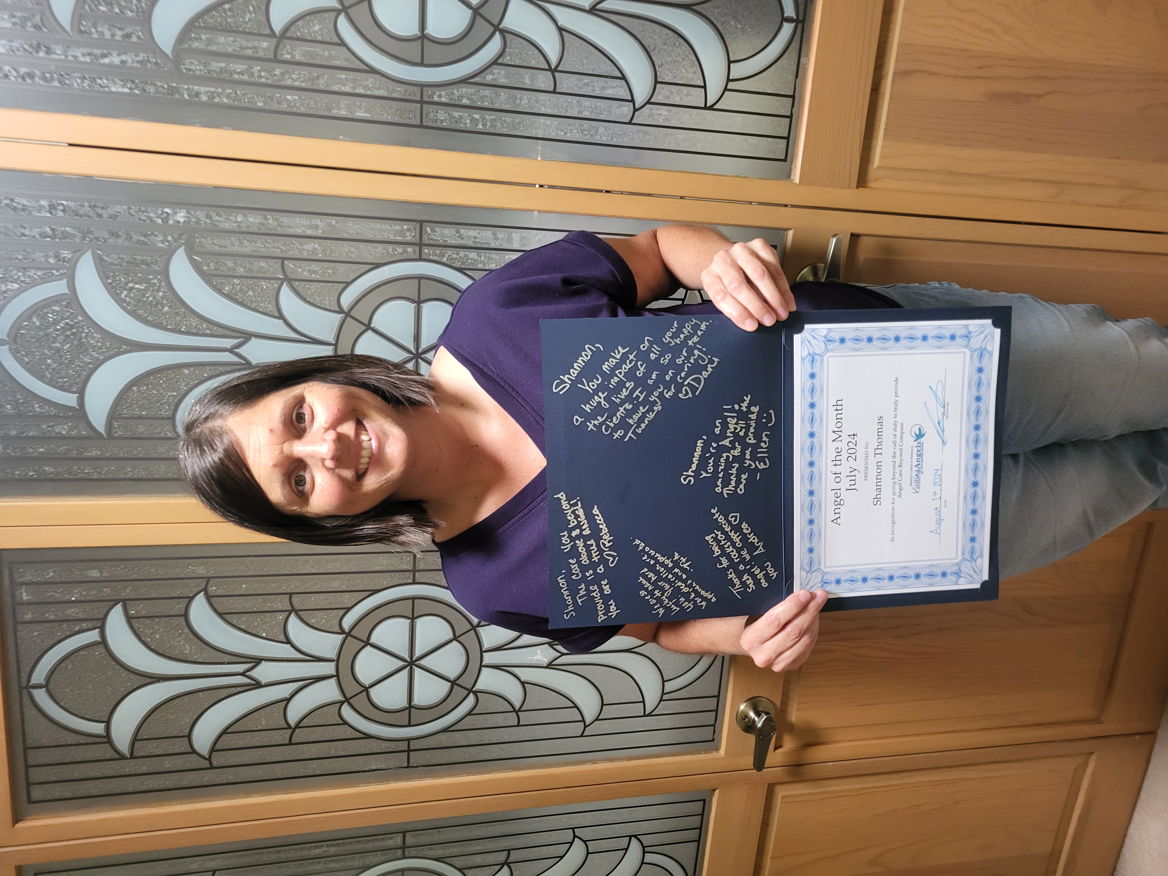 Shannon Thomas smiles and shows her printed award for Angel of the Month for excellent caregiving in home care to clients in Allegan, Kalamazoo, Mattawan, Paw Paw, Plainwell, Portage, and Southwest Michigan.