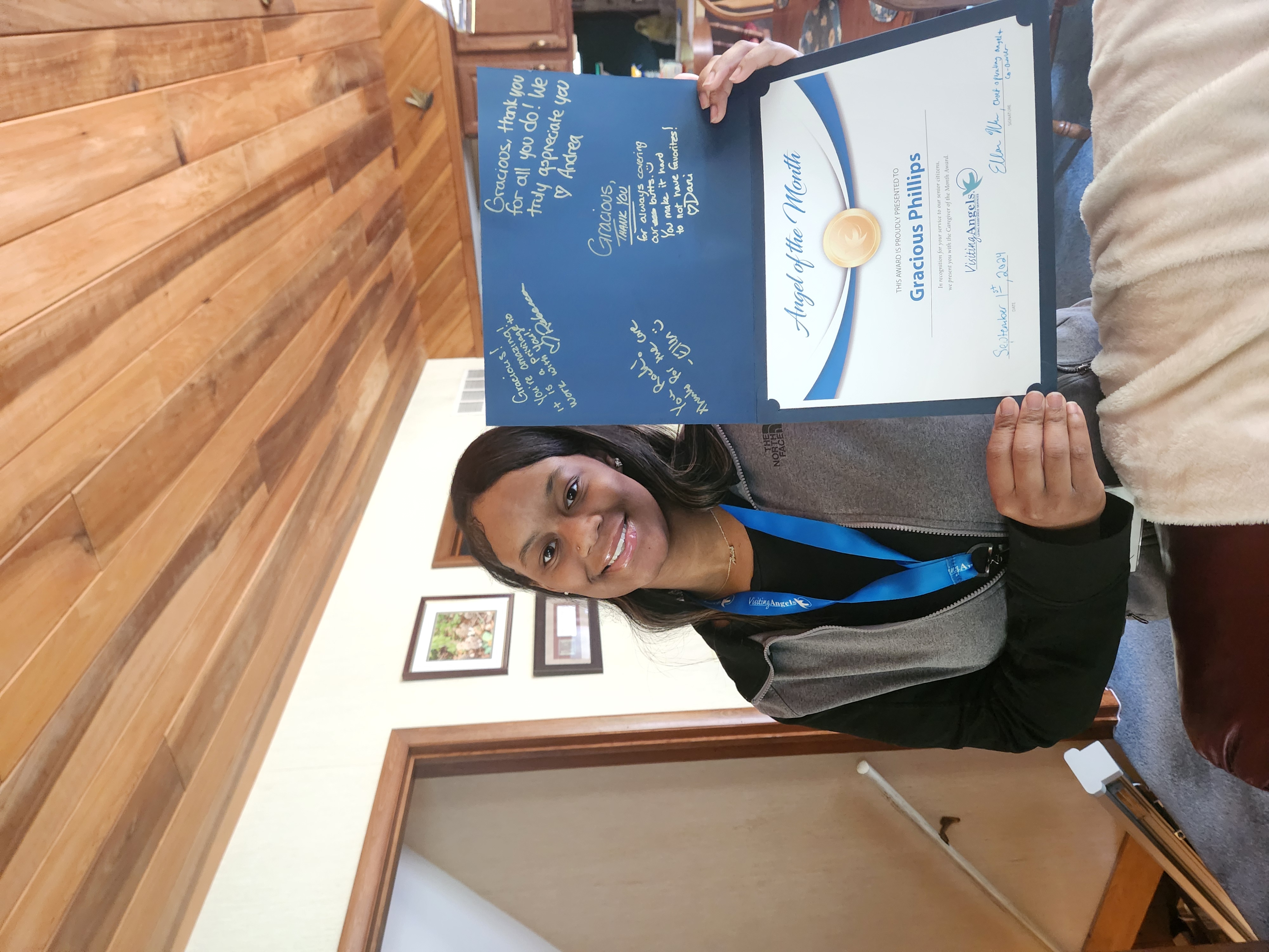 Gracious Phillips smiles and shows her printed award for Angel of the Month for September 2024 for excellent caregiving in home care to clients in Allegan, Kalamazoo, Mattawan, Paw Paw, Plainwell, Portage, and Southwest Michigan.