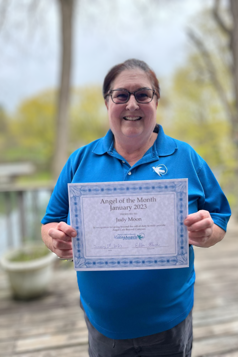 Judy Moon smiles and shows her printed award for Angel of the Month for excellent caregiving in home care to clients in Allegan, Kalamazoo, Mattawan, Paw Paw, Plainwell, Portage, and Southwest Michigan.