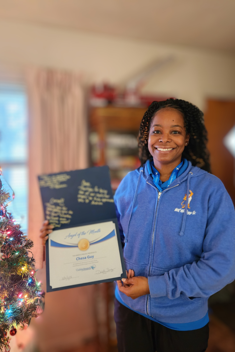 Chesa Guy smiles and shows her printed award for Angel of the Month for November 2024 for excellent caregiving in home care to clients in Allegan, Kalamazoo, Mattawan, Paw Paw, Plainwell, Portage, and Southwest Michigan.