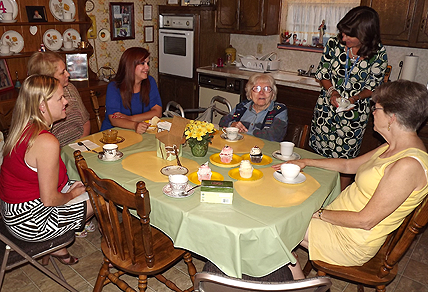 Female home care client sits at kitchen table with family and female caregiver