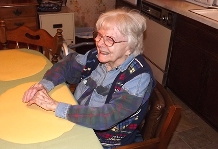 A smiling female home care client sitting in kitchen